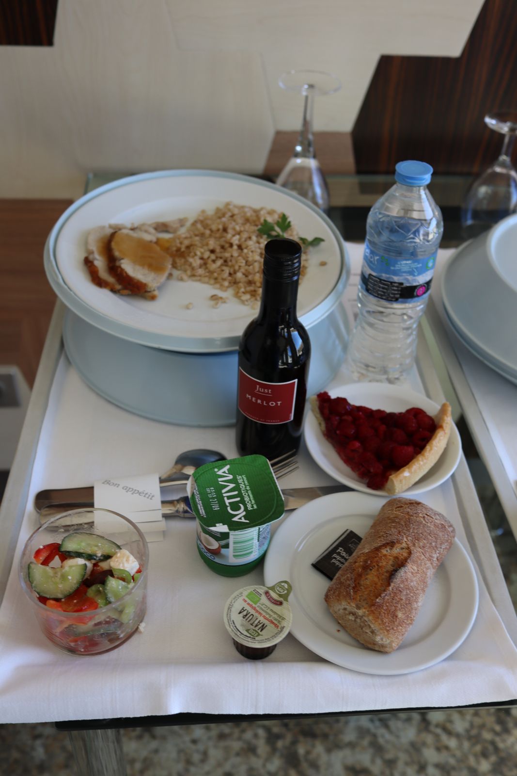 A typical meal served in the hospital room, Greek salad with dressing, roast pork with rice, raspberry tart, yogurt, water, bread and wine(proper silverware and wine glass)